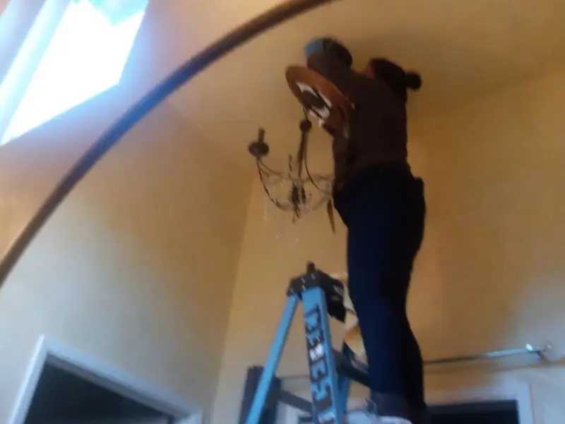 Electrician installing a chandelier in a Riverside residence